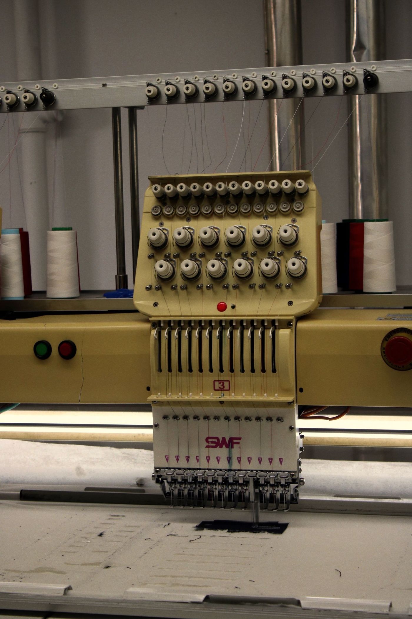 An industrial embroidery machine with thread spools in a workshop