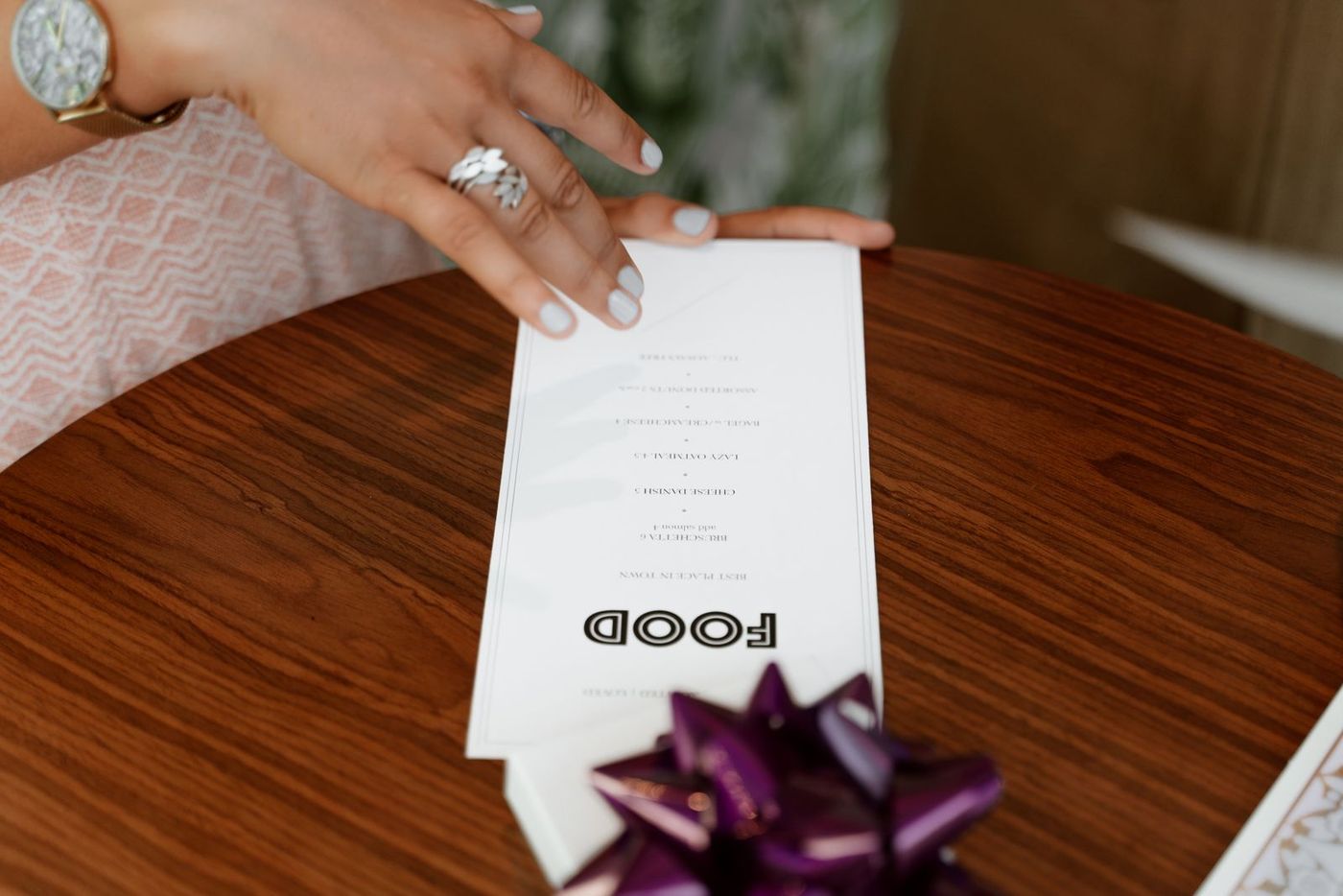 A customer holding a printed menu at a restaurant table